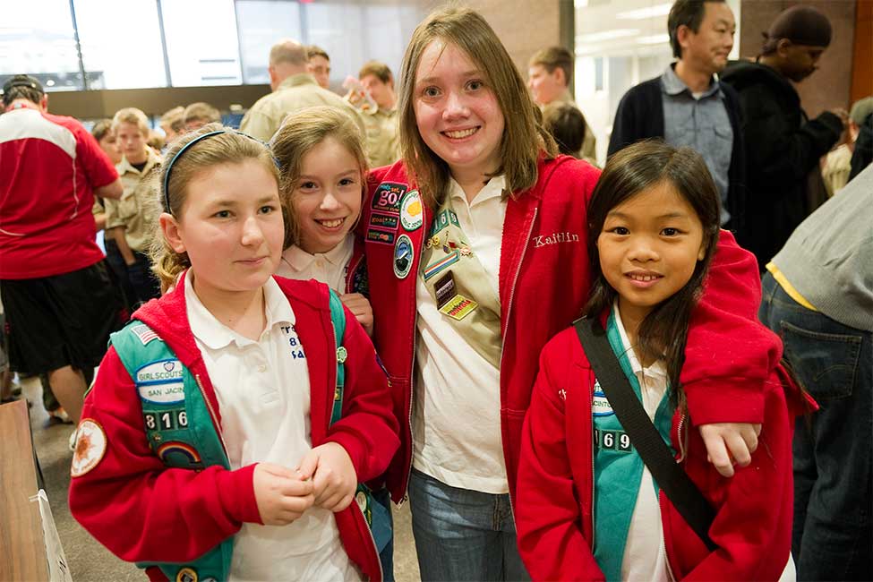 four young girls in girl scouts uniforms pose for a picture