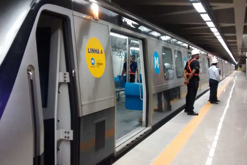 A metro train stopped at a station being inspected by construction worker. 