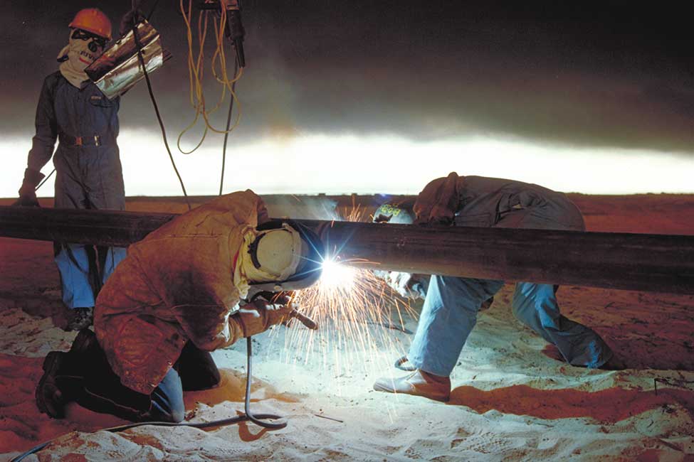 Welders work under the blanket of smoke and petroleum mist that covered most of Kuwait