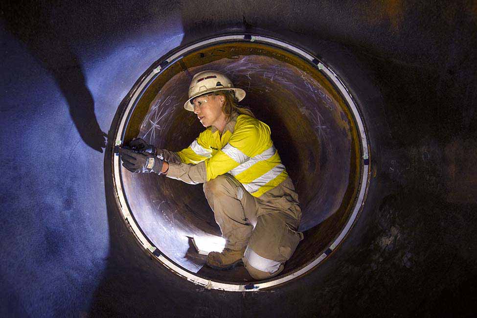 female employee inspecting a section of pipe