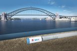The Sydney Bridge sits over a body of water, next to the Sydney Metro