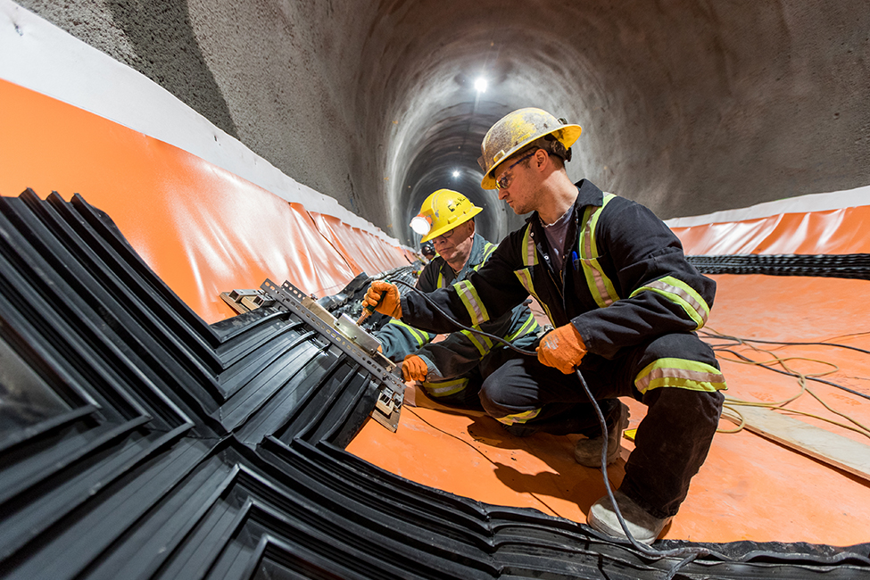 two men working on wiring inside of tunnel