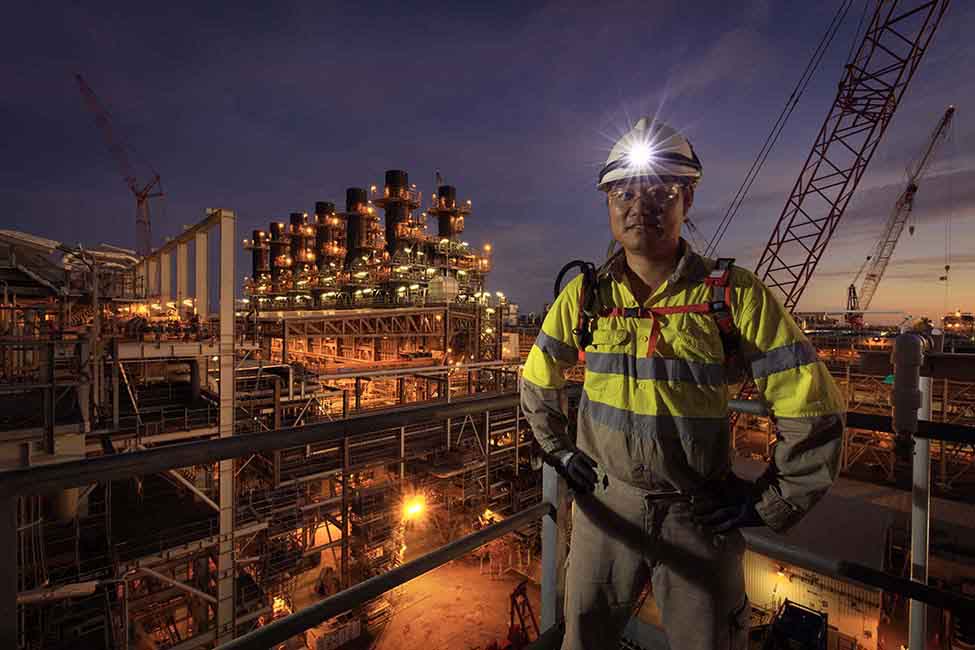 employee posing in front of Wheatstone facility at night
