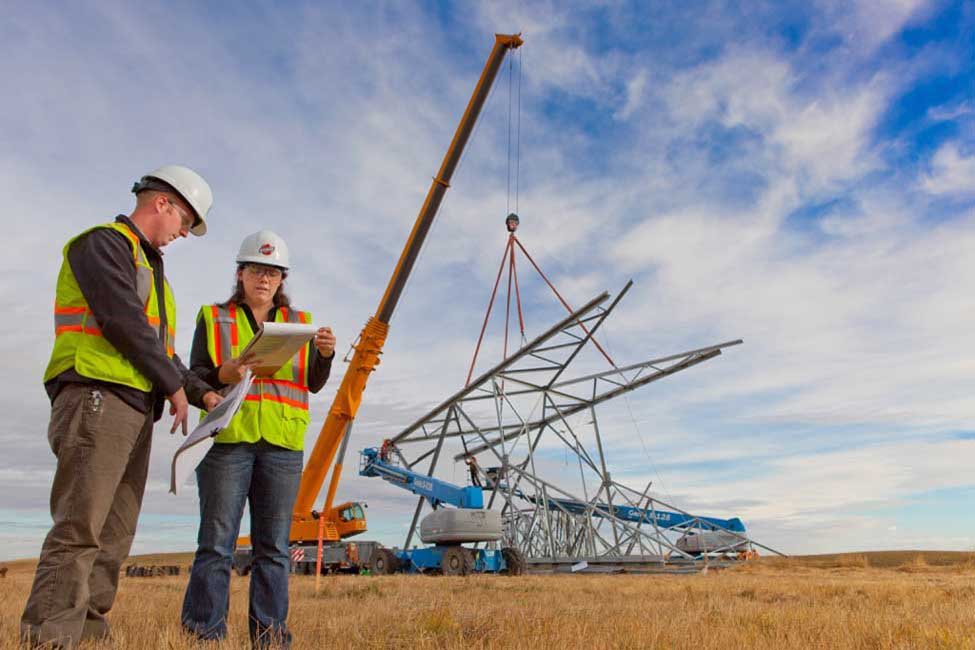 Project members oversee the assembly of transmission towers