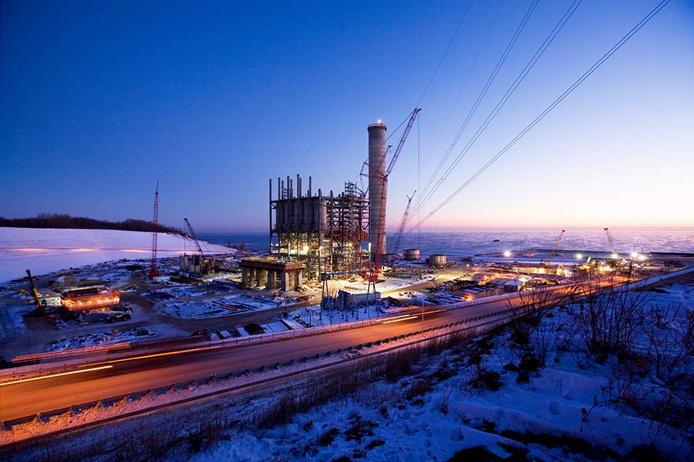 Power plant at night with snow covering ground.