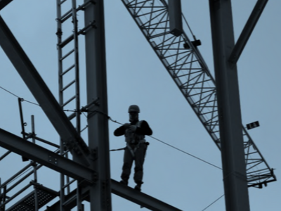 a picture of a worker high up in the air, standing on scaffolding