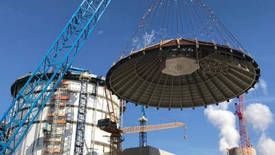 A crane lifts the conical roof onto the shield building for Plant Vogtle Unit 4.