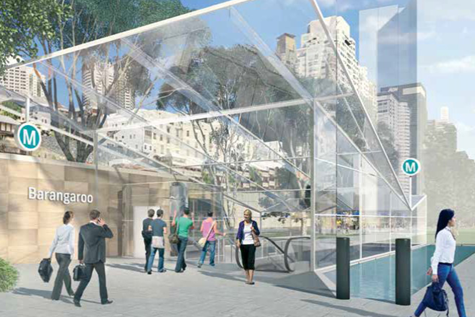 People go up and down the escalator at the Barangaroo station. Trees and buildings are shown through the glass cieling.