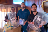 three men hold donated face shields and hand sanitizer