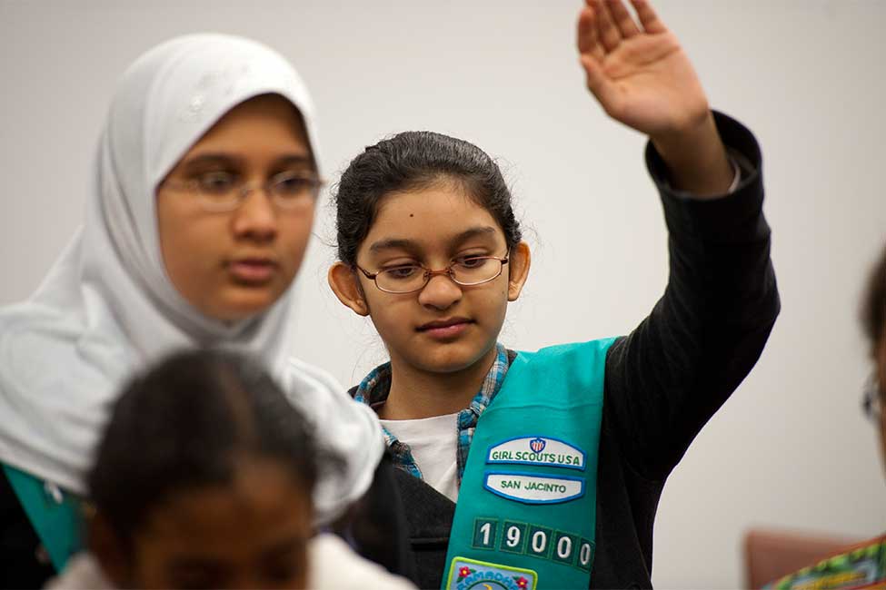 Two young women dressed as girl scouts participate in a discussion