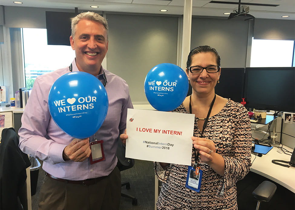 Two Bechtel employees hold a sign and balloons that read 'I love my intern'
