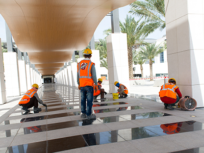 Craft workers laying tiles on a walkway. 