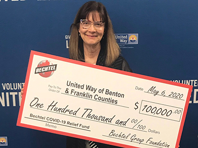 LoAnn Ayers, president and CEO of the United Way of Benton and Franklin Counties holding $100,000 check from Bechtel Group Foundation