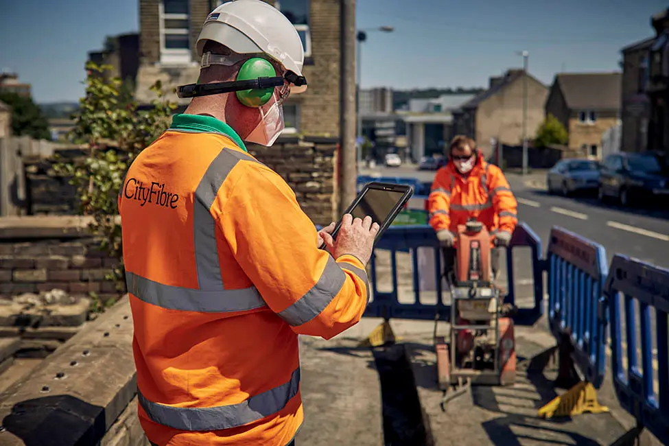 Two workers install equipment as part of the Cityfibre project.