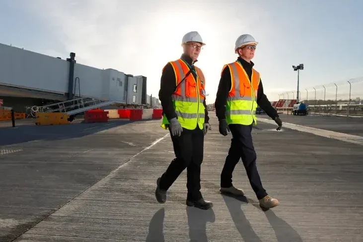 Two men walk together at jobsite.